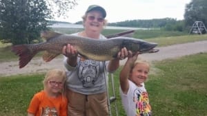 Woman with kids holding a large pike