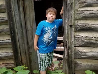 Young boy standing in a shack doorway.